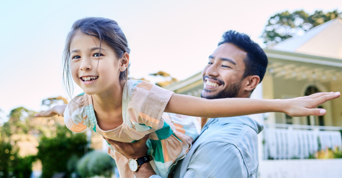 Young father holding daughter up in garden