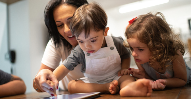 Mother with two young children at table looking at an tablet