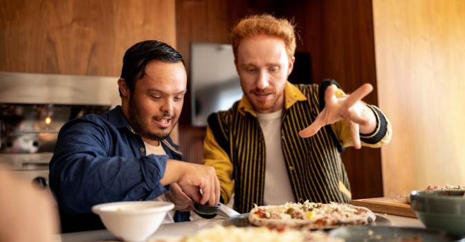 Young man with disability cooking in the kitchen with their support worker.