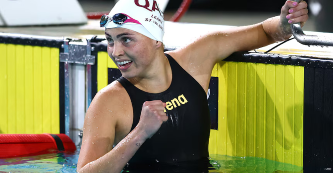 Alexa Leary with a swimming cap and goggles on her head, holding the side of the pool.