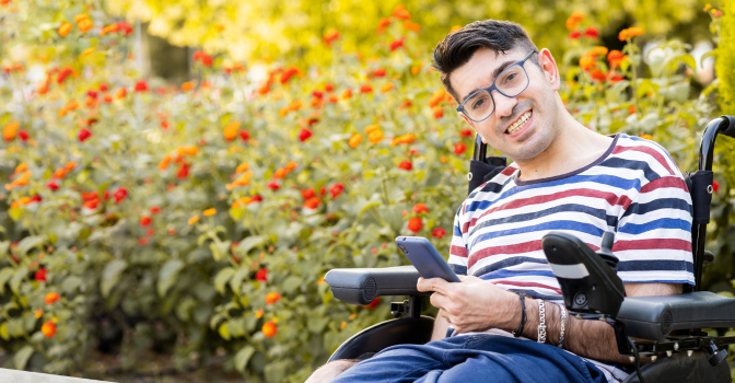 Young man in an electric wheelchair using a phone.