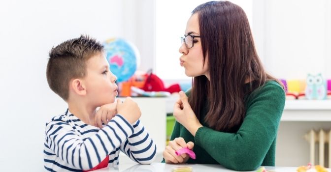 A child and his speech therapist are working together to make lip shapes and sounds.
