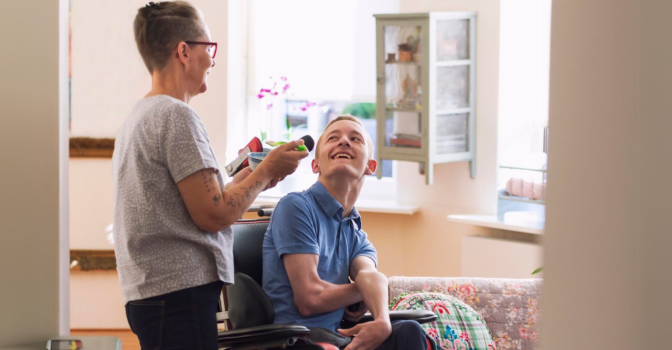 Young male using wheelchair interacting with female carer.